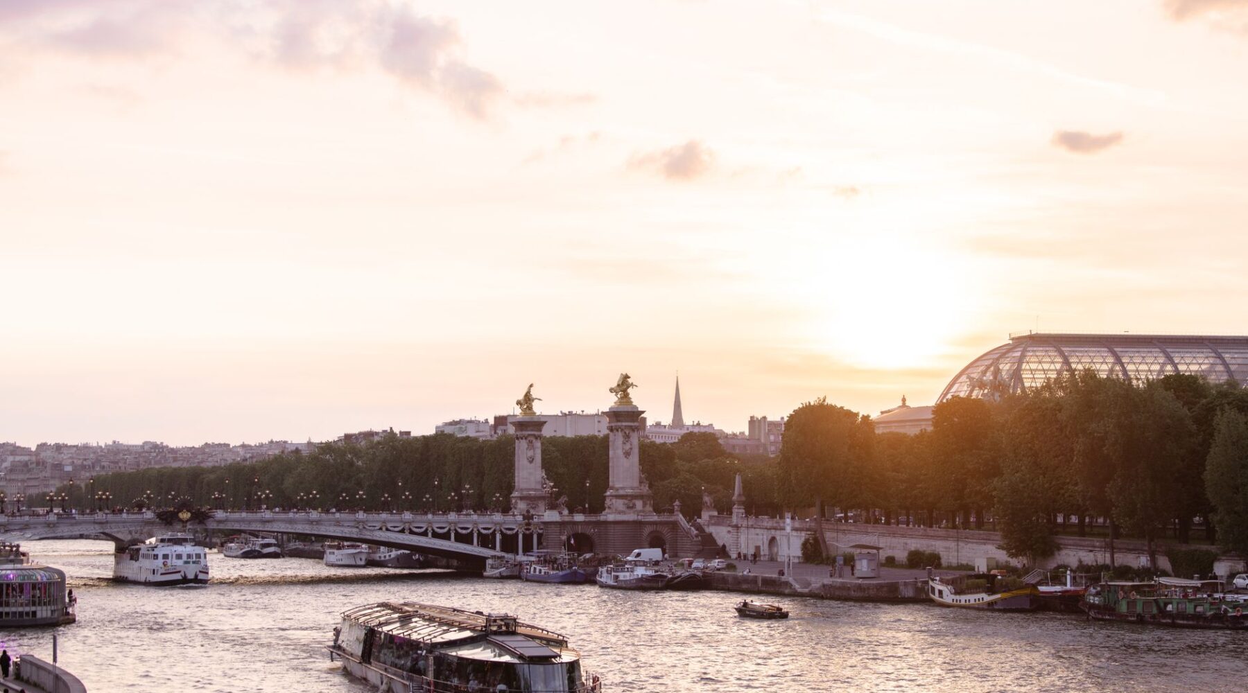 The Seine at sunset with a sightseeing boat, the gilded statues of the Pont Alexandre III and the Grand Palais roof beyond
