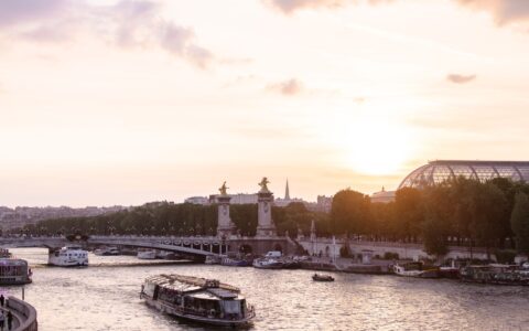 The Seine at sunset with a sightseeing boat, the gilded statues of the Pont Alexandre III and the Grand Palais roof beyond