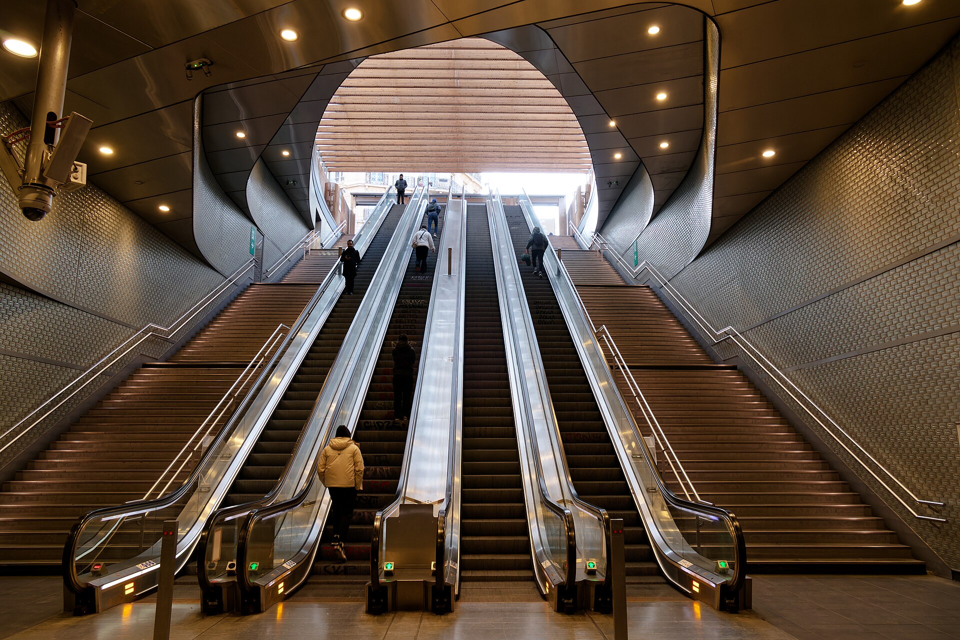 Long escalators and staircases rising through the concourse of a large Paris underground station