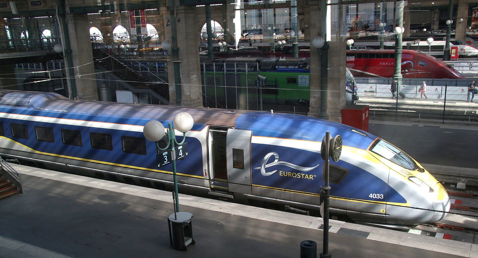 A blue and yellow Eurostar e320 high-speed train at a platform inside Gare du Nord in Paris