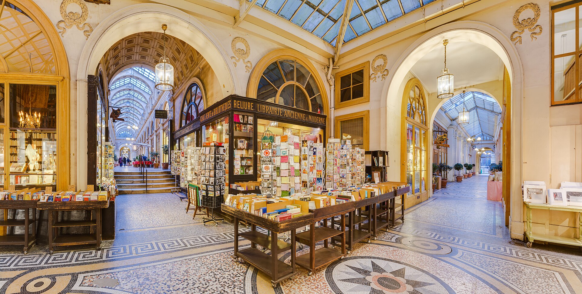 The glass-roofed Galerie Vivienne arcade in Paris, with a mosaic floor, an antiquarian bookshop and hanging lanterns