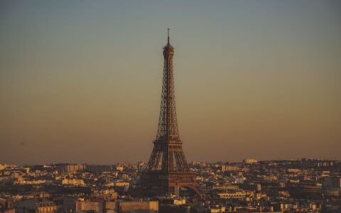 The Eiffel Tower rising above the Paris rooftops at dusk under a warm golden sky
