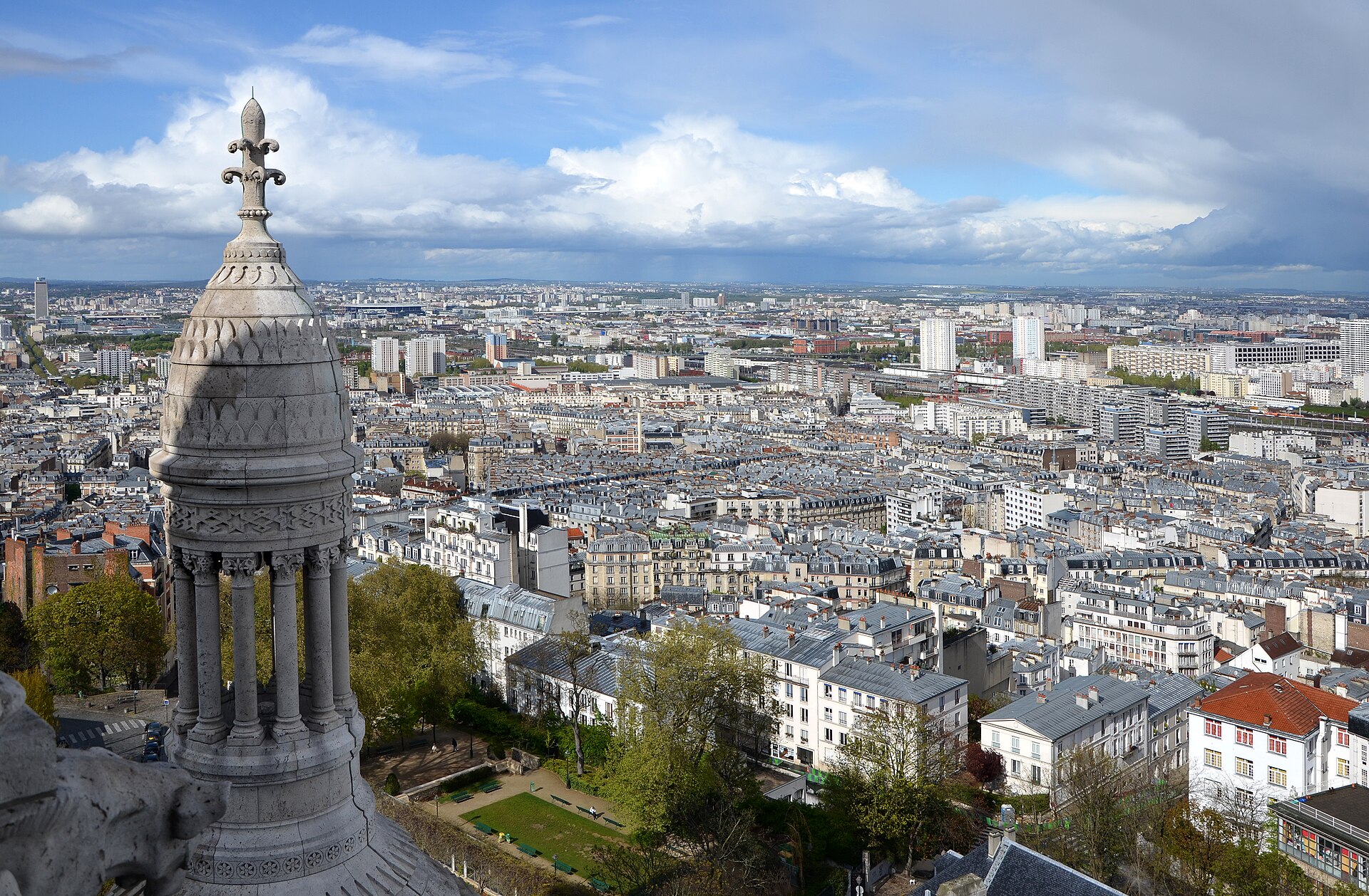 North-east Paris seen from the dome of Sacré-Cœur, with a stone turret in the foreground and rooftops stretching to the horizon