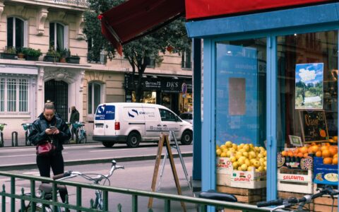 A blue-framed greengrocer's shop in Paris with crates of lemons and oranges on the pavement and a chalked price board