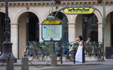 The Art Nouveau Metropolitain entrance at Palais Royal-Musée du Louvre with the network map, bicycles and passers-by