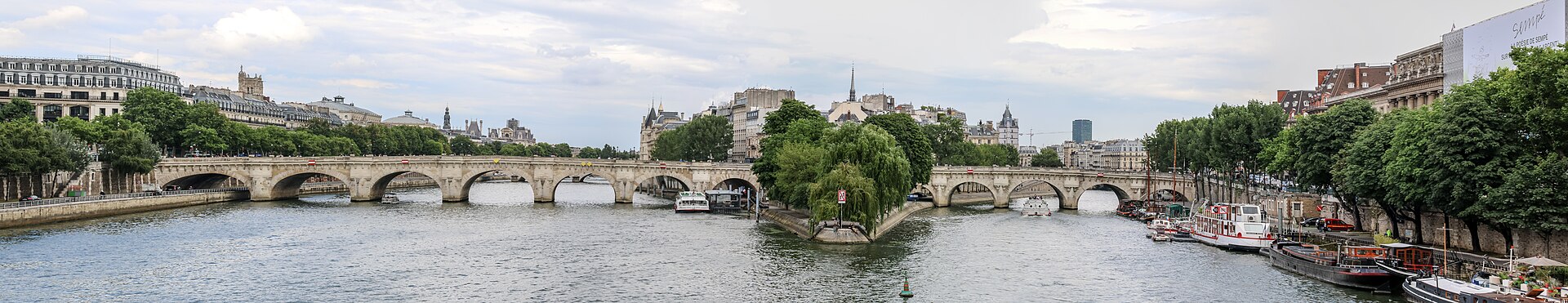 Panoramic view of the Seine with the Pont Neuf crossing to the tip of the Ile de la Cite, willow trees and moored boats