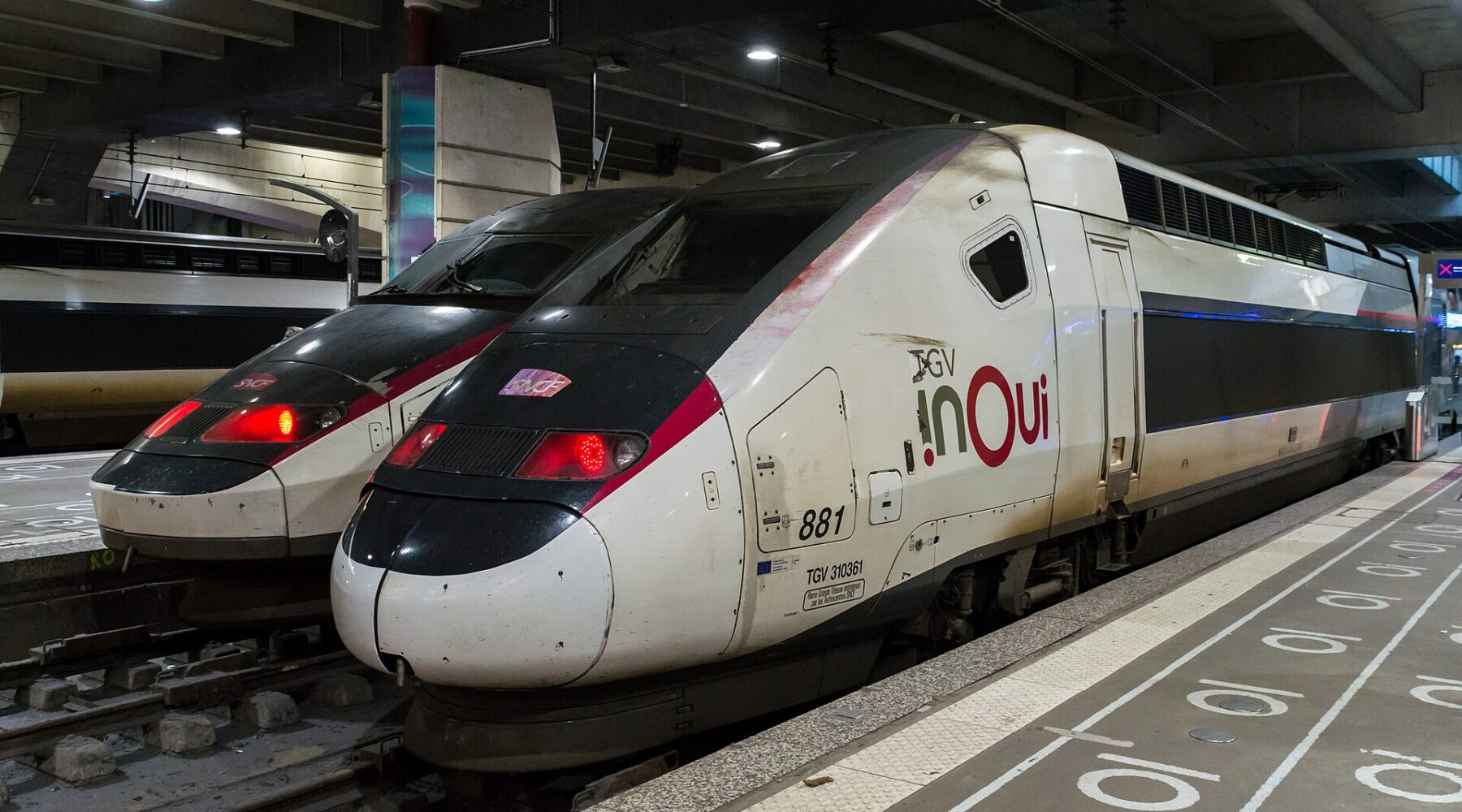 A white TGV INOUI double-decker high-speed train standing at a covered platform in Gare Montparnasse