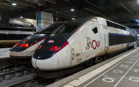 A white TGV INOUI double-decker high-speed train standing at a covered platform in Gare Montparnasse