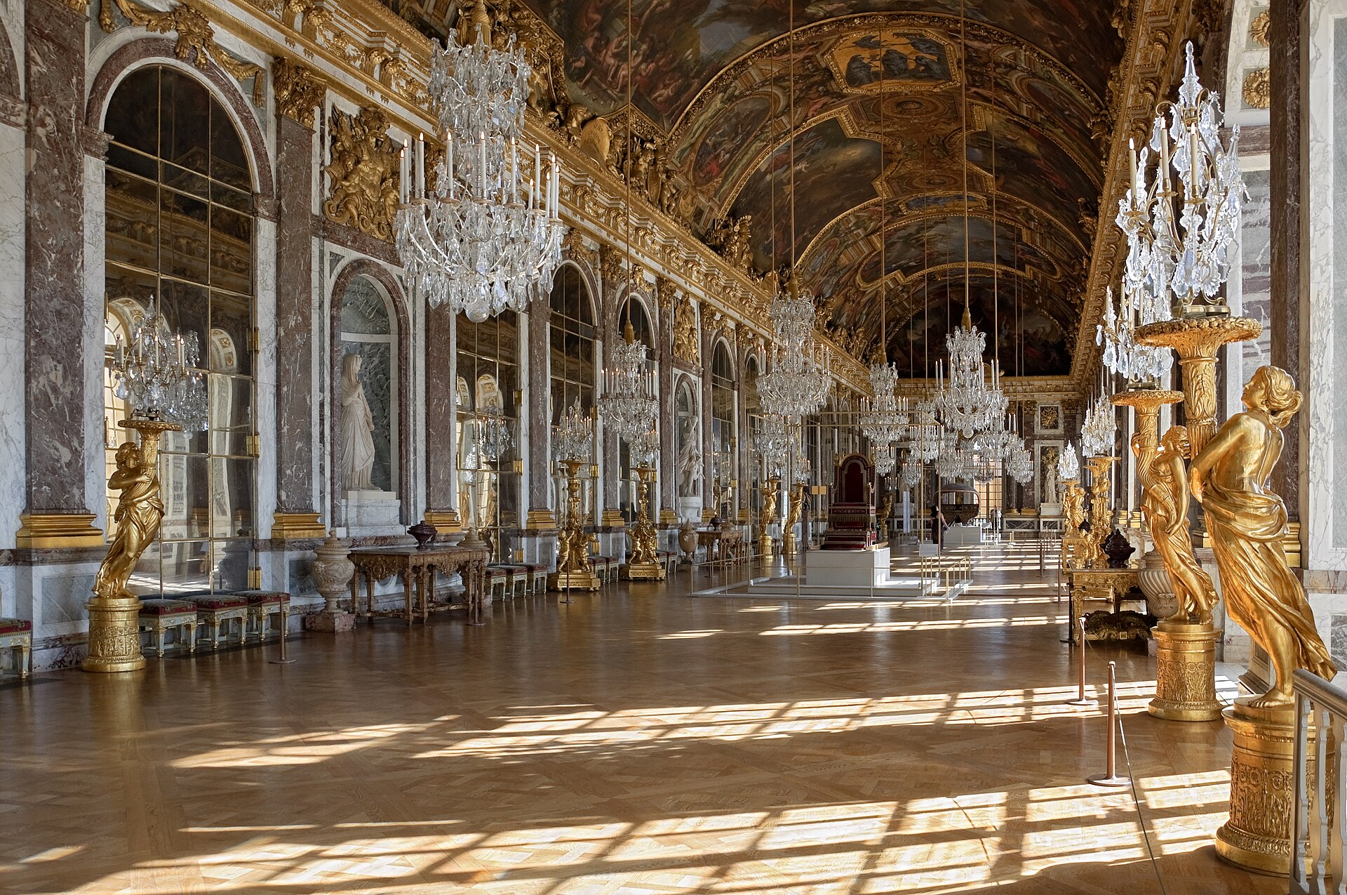 The Hall of Mirrors at the Chateau de Versailles with arched mirrors, crystal chandeliers and a painted vaulted ceiling