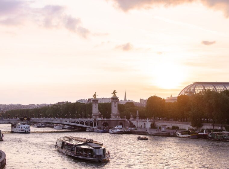 Sunset over the Seine in Paris, with a sightseeing boat on the river, the gilded statues of the Pont Alexandre III and the glass roof of the Grand Palais